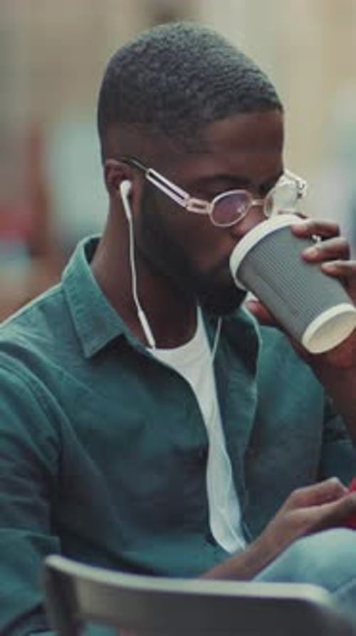 Man using smartphone, sitting outdoors in city