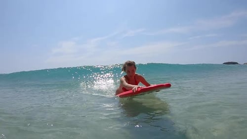 Young woman surfer haves fun in the tropical sea and surfs the small wave on the red bodyboard