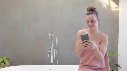 Woman Using Phone While Relaxing in Bathroom