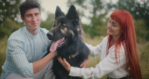 Couple petting their dog outdoors in a field