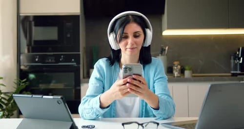 Woman Using Phone with Laptop and Tablet
