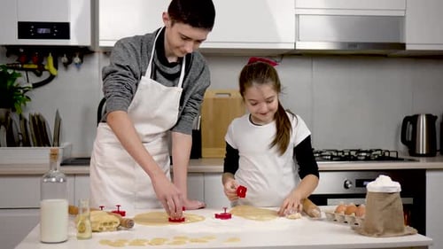 Boy and Girl Wearing Apron Cutting Dough with Cookie Cutter in Cozy Kitchen Children Making Cakes