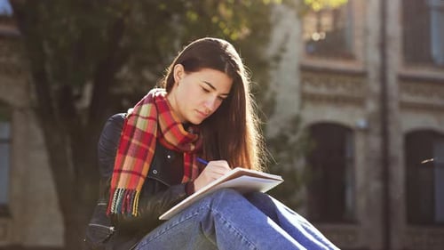 Girl Writes in Notebook Outdoors on Sunny Day
