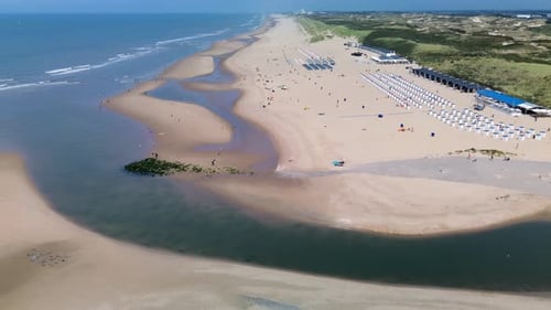 A beautiful aerial view of a sandy beach with rows of beach huts, people relaxing by the shore