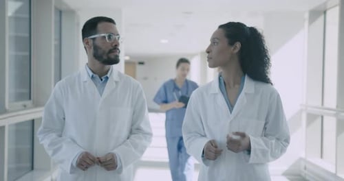 Doctors Walking in Hospital corridor and Discussing treatment