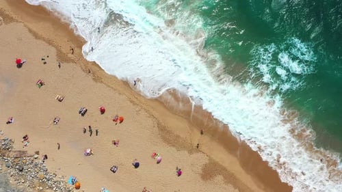 Beachgoers Enjoying the Sunny Day on Sandy Beach with Sea Waves Crashing