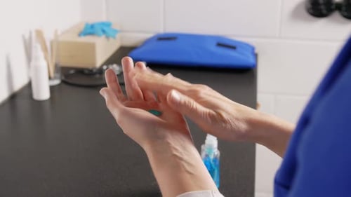 Doctor sprays antibacterial hand sanitizer at hospital in slow motion