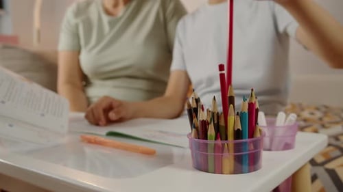 Kind wählt Buntstift, während es mit Großmutter studiert