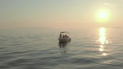 Close up aerial shot of a boat anchored in the middle of calm Mediterranean sea at sunset.