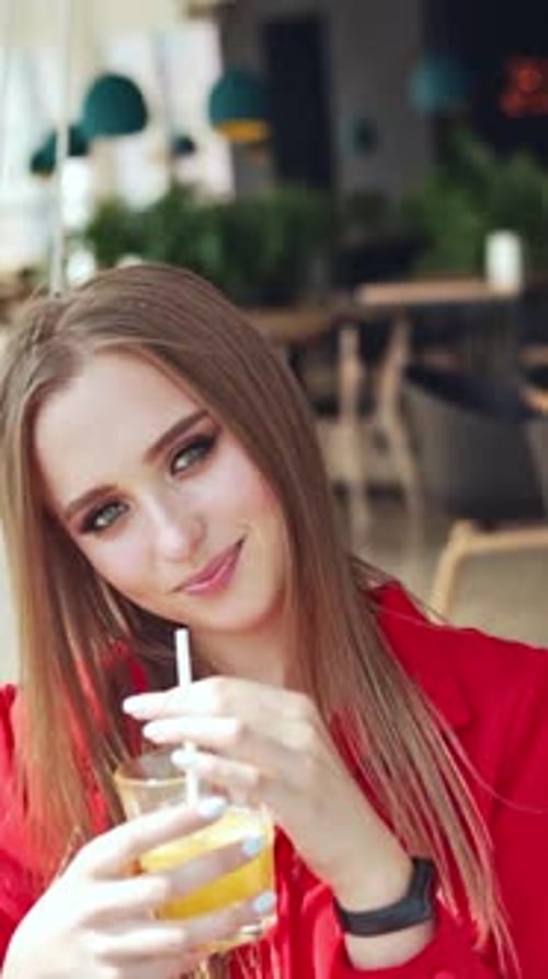 Woman sitting and drinking juice. Pretty young woman sitting in cafe with cup of juice.