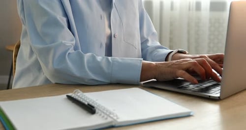 Typing on Laptop and Writing in Notebook