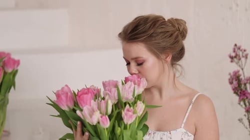 Woman Smelling a Bouquet of Pink Tulips