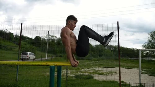 Man Does Bar Exercises in the Park