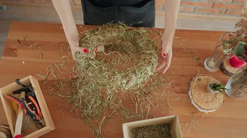 Woman Creates Floral Wreath at Wooden Table Indoors