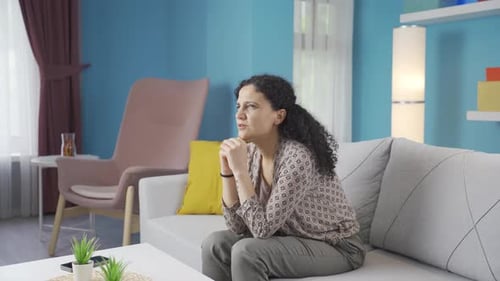 Worried Woman Sits on Couch in Living Room