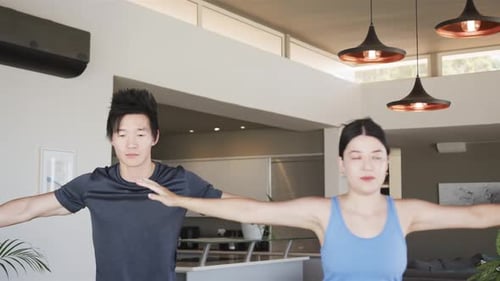 Casal chinês iniciando a rotina, levantando, estendendo os braços, vestindo roupas de ginástica para ioga em casa em tapetes