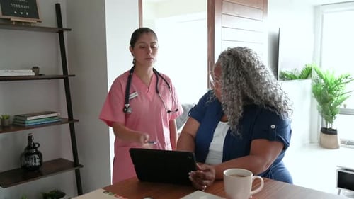 Home Healthcare Nurse Consults with Senior Woman on Tablet