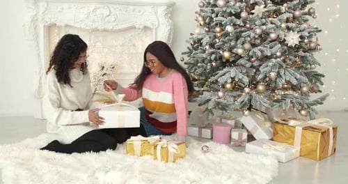 Friends Opening Christmas Gifts Together Indoors at Home