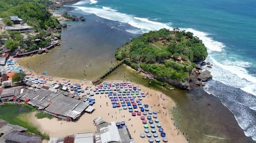 Drohnenaufnahme von Drini Beach in Yogyakarta, Indonesien, mit bunten Sonnenschirmen,
