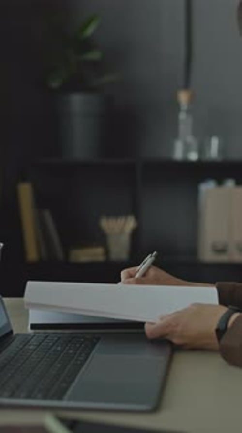 Businesswoman Using Laptop while Doing Paperwork in Office