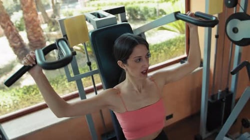 Woman Using Weight Machine at Sunny Gym