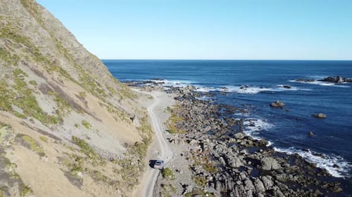 Slowly following a truck as it drives along a gravel coastal road.