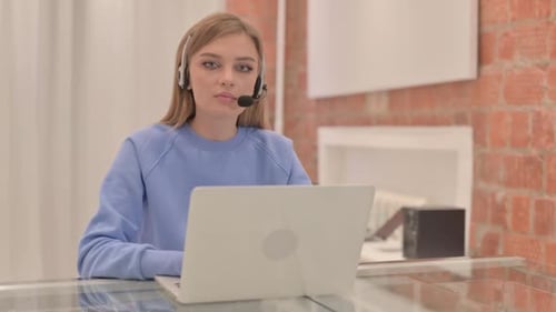 Young Woman with Headset Looking toward Camera in Call Center