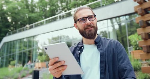 Man using tablet in green urban setting daytime