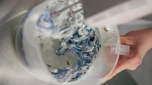 Vertical Video Closeup of Female Baker in a Professional Kitchen Mixing Cream and Dye with a Mixer
