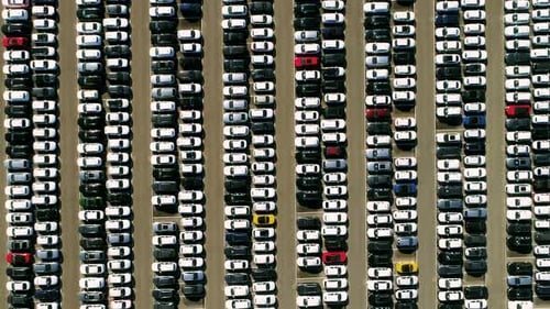 Aerial footage of finished cars ready to be shipped on huge distribution center