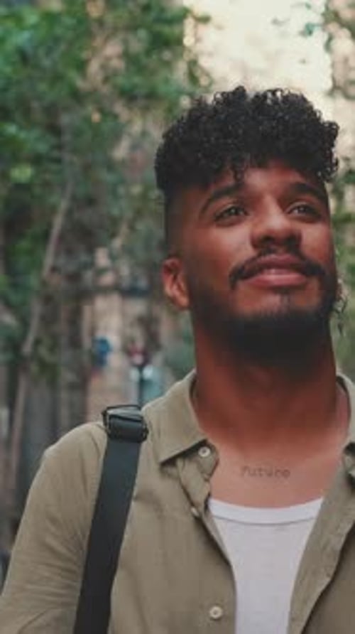 Close up, young smiling man walks along the narrow street of the old city and looks around