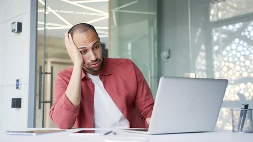 Man Working at Laptop in Modern Office, Bored