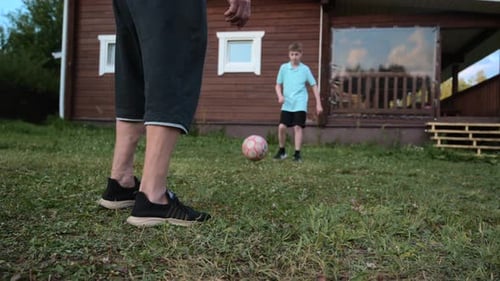 Adult and Boy Play Soccer on Lawn