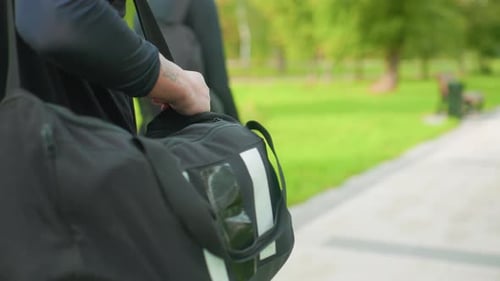 Individual Adjusting Bag on Pathway Close View of Man Handling Travel Bag Detailed Shot Capturing