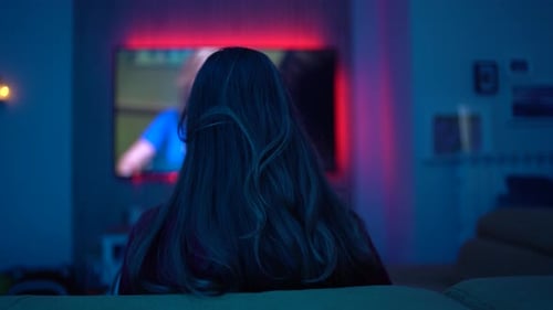 Woman Watching Television in Dark Room at Night