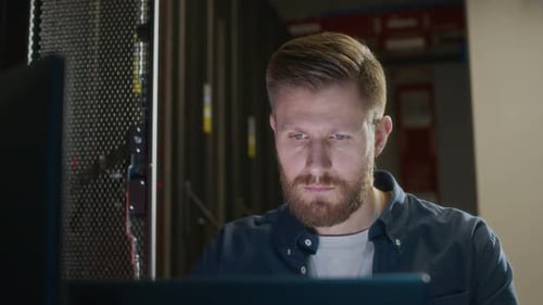 Young Concentrated Male IT Administrator Working with Coding in Data Center