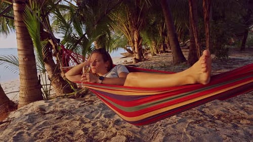 Woman Relaxing in Hammock at Tropical Beach Sunset