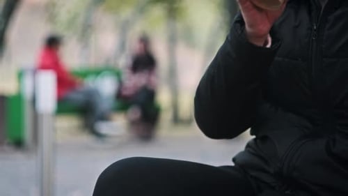 Young Woman Drinks Coffee From Paper Cup on Bench in an Autumn Park