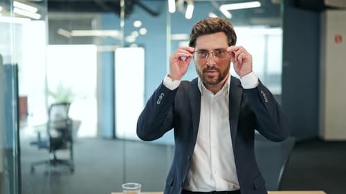 Professional Man Puts on Glasses, Smiles in Office