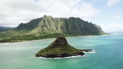 Tiro de drone se aproximando do chapéu do homem chinês (Mokoli'i) com a cordilheira de Kualoa ao fundo.