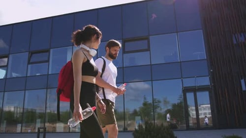 Caucasian Relaxed Young People Male and Female in Sporty Style Walking the City Talking and Holding