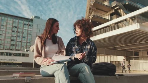 Die Schüler teilen emotional die Neuigkeiten und lachen, während sie neben der Universität sitzen