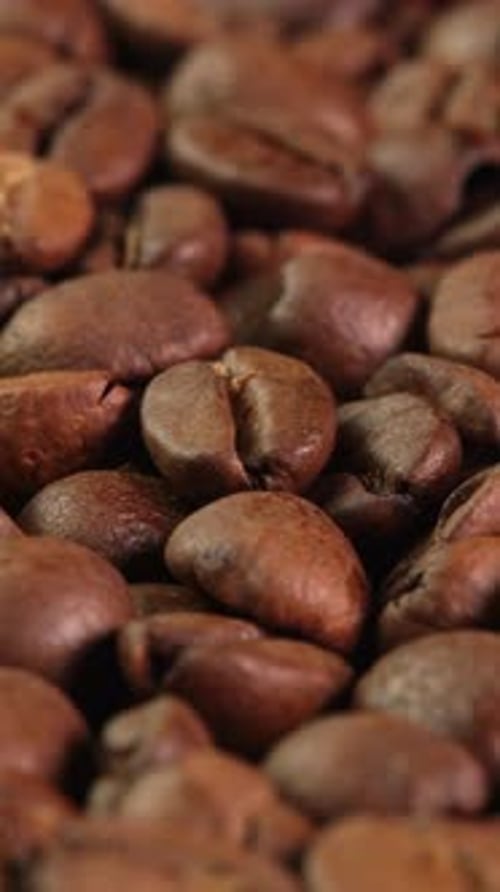 Vertical video roasted coffee beans rotating as background close-up macro. Concept for coffee shop