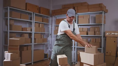 A Positive Male Movers in Uniform Dancing in a Warehousefolding Boxes of Parcels