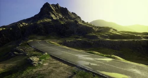 Estrada sinuosa panorâmica que leva a uma montanha majestosa ao nascer do sol