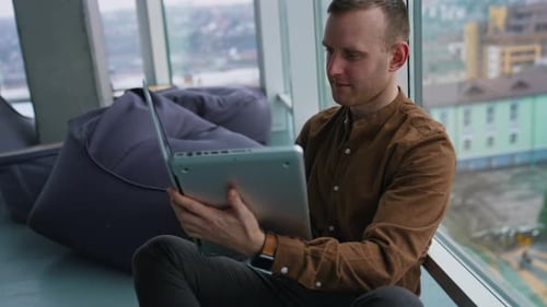 Handsome man sitting on floor using laptop
