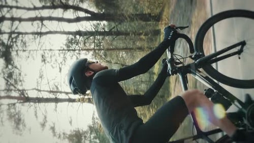 Man Cycling on Road Next to Trees