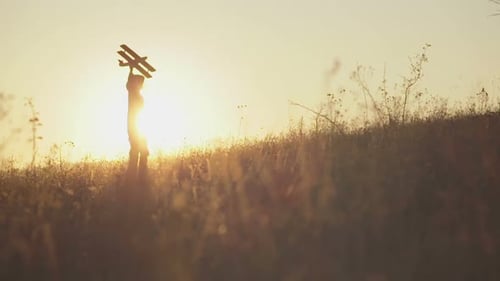 Boy Holds Toy Airplane Toward Golden Sunset