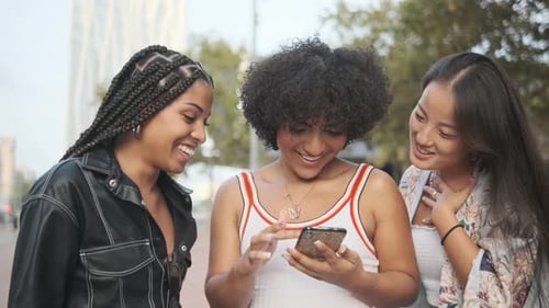 Three Young Women Friends Using Smartphone on City Street