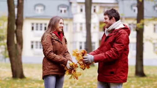 Couple Playing with Autumn Leaves in the Park